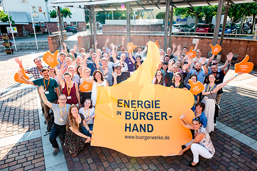 Große Gruppe Menschen posiert mit einem Werbebanner "Energie in Bürgerhand"